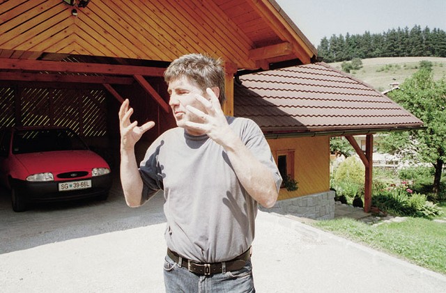 '<I>Tukaj se je zgodilo, lanskega 28. februarja</I>.' Miro Petek na kraju zločina. Zadaj je garaža, od koder sta planila napadalca. Za garažo je hrib, na vrhu cesta, kjer je eksekutorja v avtu čakal šofer. Državna meja je blizu. Napad se je zgodil malo pred enajsto zvečer. Zunaj je ravno naletaval sneg.